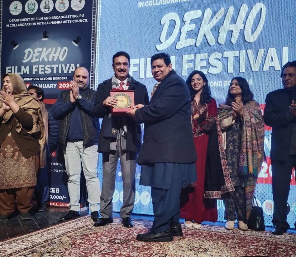 A commemorative shield being presented on stage at the DEKHO Film Festival